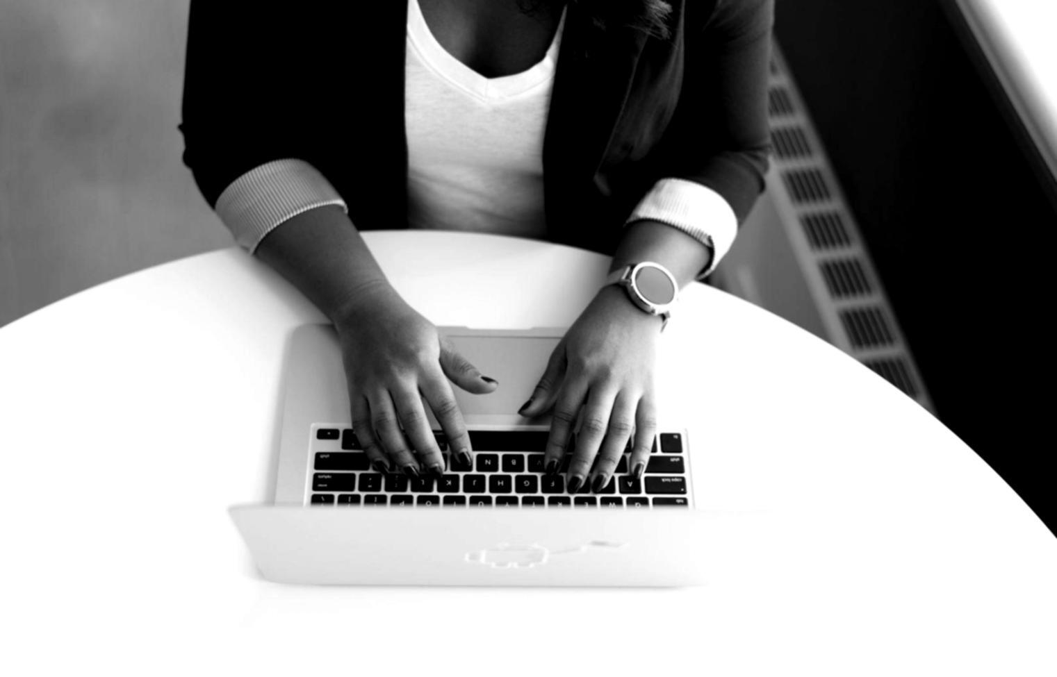 Persona estudiando finanzas desde casa con múltiples dispositivos y materiales educativos